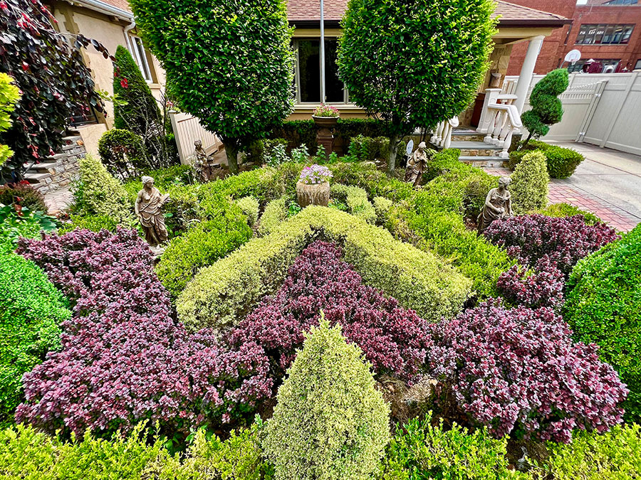 arrangement of bushes in front of a house with statuettes of nymphs throughout